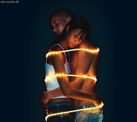 man and woman holding each other with rope lights wrapped around them
